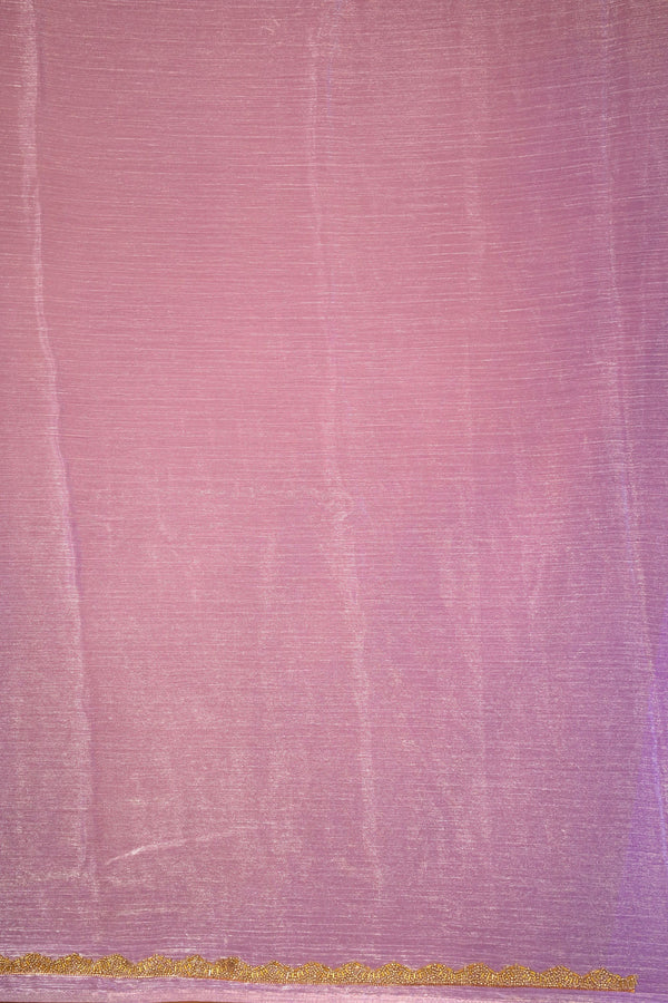 A close-up of a pink fabric surface with a fine textured weave and a narrow horizontal band of gold pattern along the bottom edge.