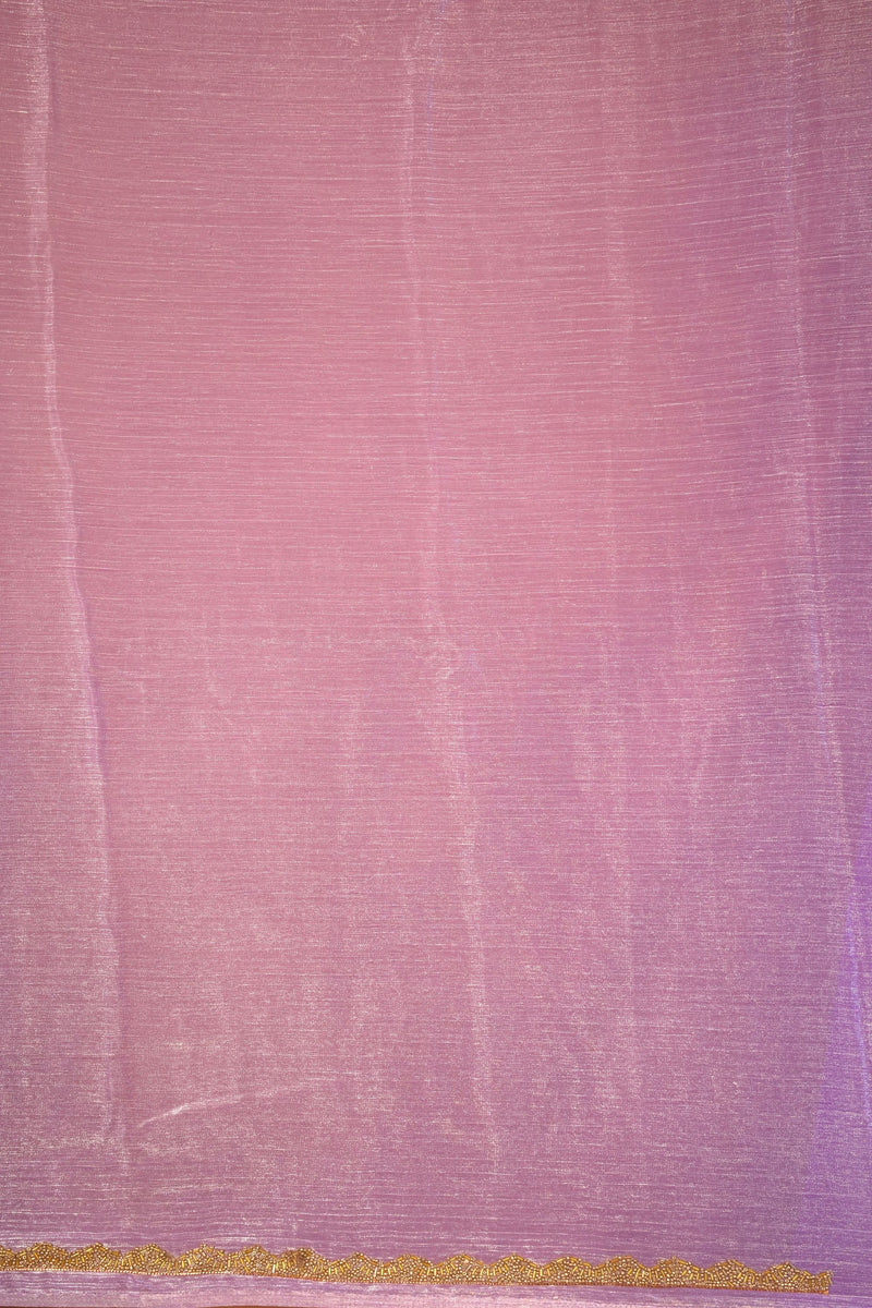 A close-up of a pink fabric surface with a fine textured weave and a narrow horizontal band of gold pattern along the bottom edge.