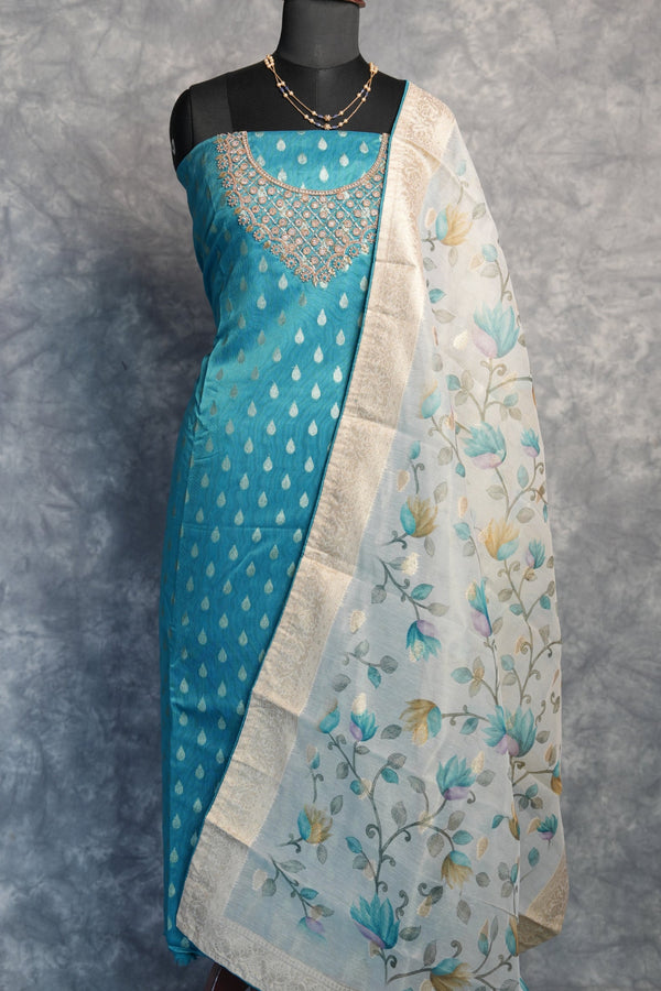 Two pieces of fabric, one blue with white patterns and the other floral, on a gray surface.