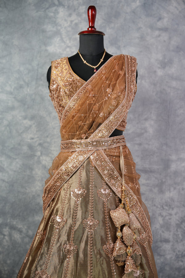 Antique Gold Lehenga Choli - with rich zari & sequin embroidery, floral medallion motifs, scalloped border, rose-gold threadwork, gracefully draped dupatta & ornate tassel detailing. Ideal for bridal & festive celebrations.