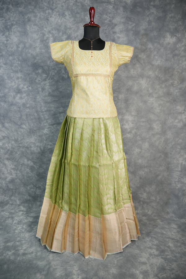 Green and beige traditional outfit on a mannequin against a gray background