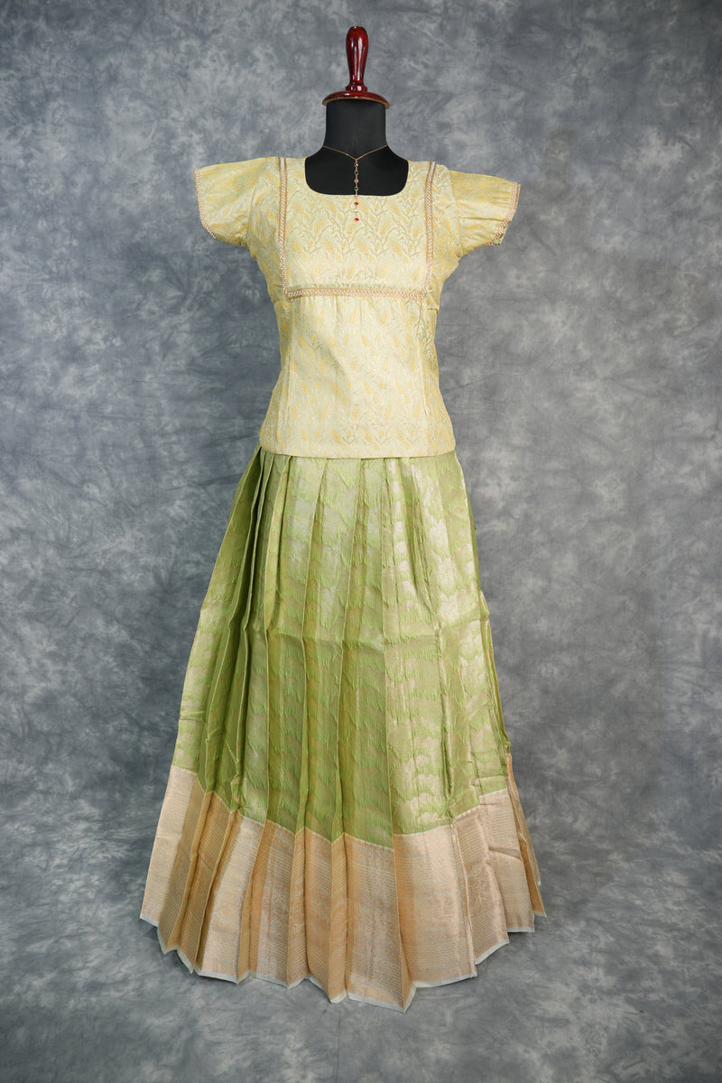 Green and beige traditional outfit on a mannequin against a gray background