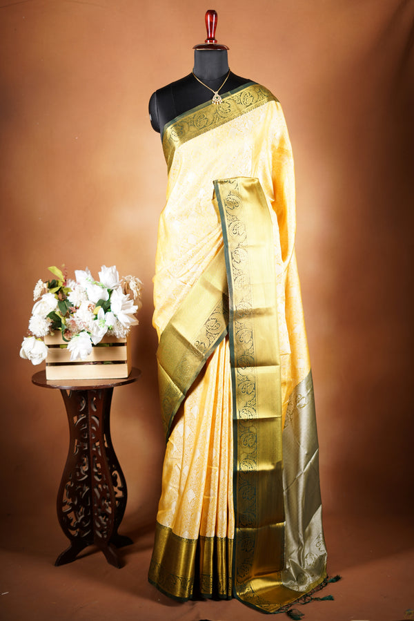 Ivory GoldTissue Cotton Saree-subtle sophistication with this elegant yellow tissue cotton saree, complemented by a deep green zari border. The fabric carries a refined shimmer with intricate woven patterns that add depth and texture to the overall look.