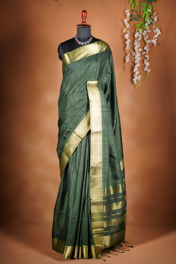 Antique Gree Semi Tussar Saree - Deep, rich Green with a luminous golden finish.Premium Features a wide, lustrous golden zari border and a grand pallu adorned with classic horizontal stripes and delicate tassel accents