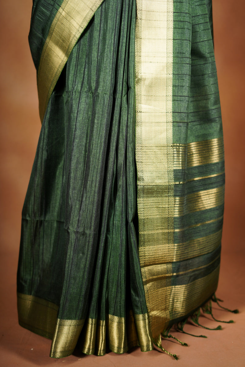 Antique Gree Semi Tussar Saree - Deep, rich Green with a luminous golden finish.Premium Features a wide, lustrous golden zari border and a grand pallu adorned with classic horizontal stripes and delicate tassel accents