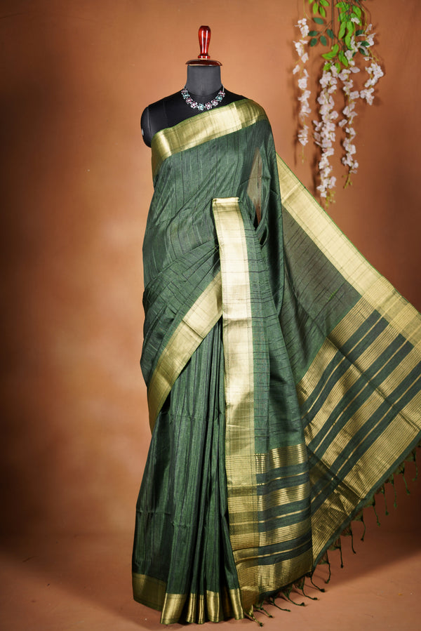 Antique Gree Semi Tussar Saree - Deep, rich Green with a luminous golden finish.Premium Features a wide, lustrous golden zari border and a grand pallu adorned with classic horizontal stripes and delicate tassel accents