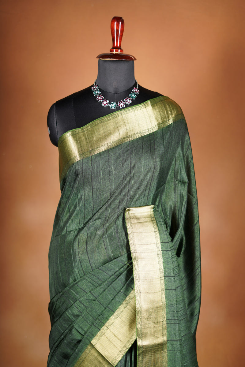 Antique Gree Semi Tussar Saree - Deep, rich Green with a luminous golden finish.Premium Features a wide, lustrous golden zari border and a grand pallu adorned with classic horizontal stripes and delicate tassel accents