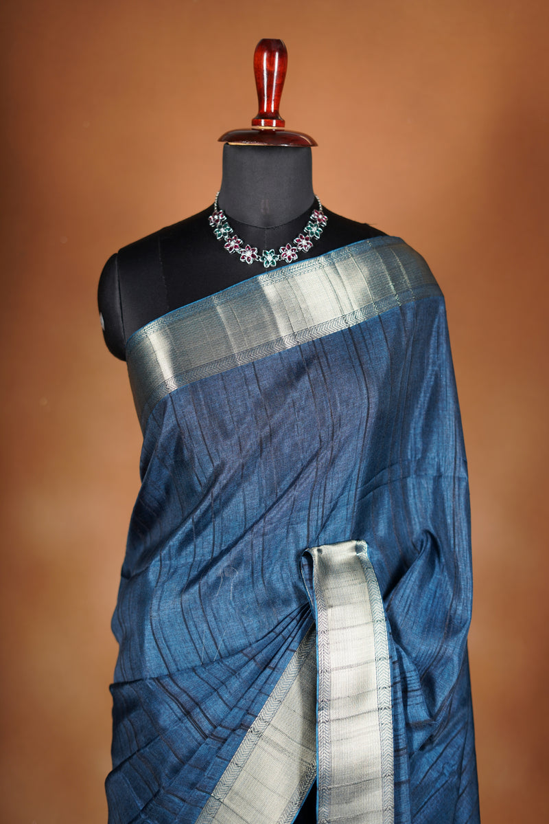 Dark slate blue Semi Tussar - Features a contrasting silver zari border and a grand pallu detailed with classic horizontal stripes and matching tassel fringe.