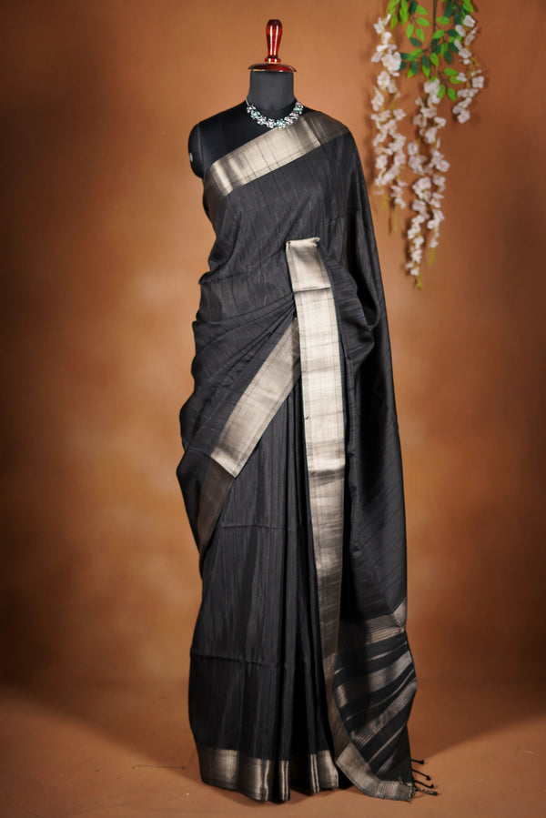 Fade Black Semi Tussar - designed to capture attention with its luxurious appeal. The vibrant tone is enhanced by delicate texture detailing and a lustrous zari border that adds depth and richness.
