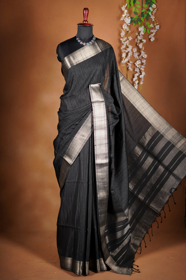 Fade Black Semi Tussar - designed to capture attention with its luxurious appeal. The vibrant tone is enhanced by delicate texture detailing and a lustrous zari border that adds depth and richness.