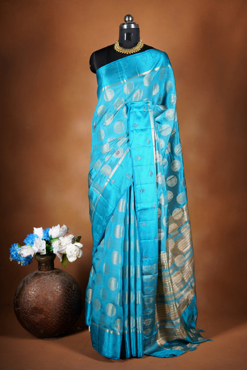 Aqua Blue Fancy semi jute saree - It features an elegant gold zari border with fine woven detailing and a matching zari pallu. The body has small round gold butta motifs, evenly spread for a subtle  traditional look with a matching blouse.