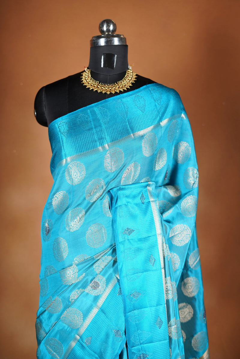 Aqua Blue Fancy semi jute saree - It features an elegant gold zari border with fine woven detailing and a matching zari pallu. The body has small round gold butta motifs, evenly spread for a subtle  traditional look with a matching blouse.