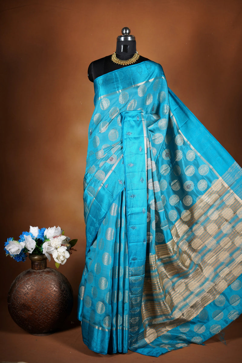 Aqua Blue Fancy semi jute saree - It features an elegant gold zari border with fine woven detailing and a matching zari pallu. The body has small round gold butta motifs, evenly spread for a subtle  traditional look with a matching blouse.