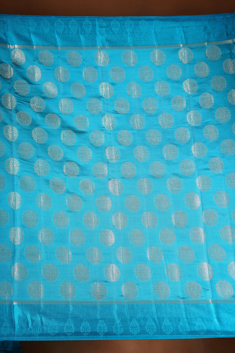 Aqua Blue Fancy semi jute saree - It features an elegant gold zari border with fine woven detailing and a matching zari pallu. The body has small round gold butta motifs, evenly spread for a subtle  traditional look with a matching blouse.