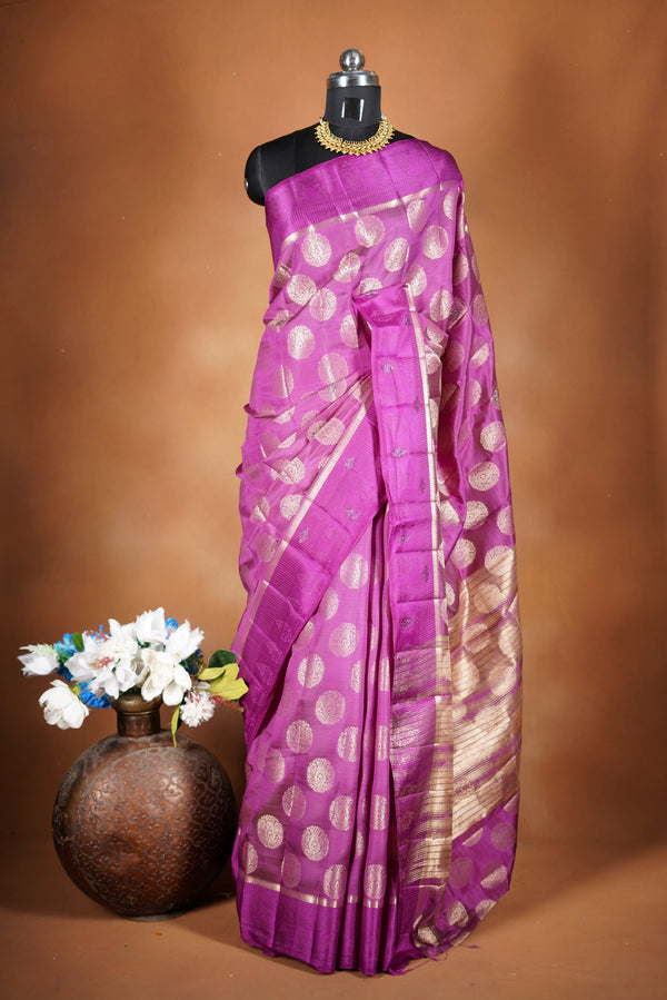 Magenta  Fancy semi jute saree - It features an elegant gold zari border with fine woven detailing and a matching zari pallu. The body has small round gold butta motifs, evenly spread for a subtle  traditional look with a matching blouse.