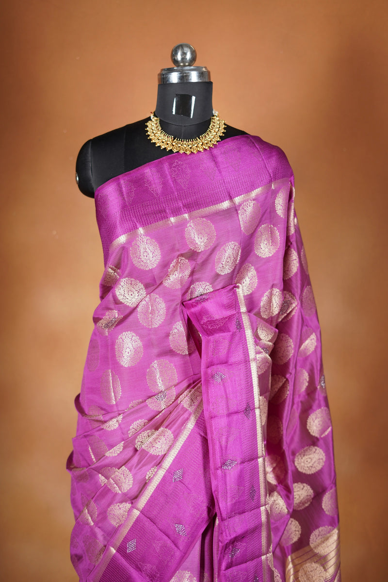 Magenta  Fancy semi jute saree - It features an elegant gold zari border with fine woven detailing and a matching zari pallu. The body has small round gold butta motifs, evenly spread for a subtle  traditional look with a matching blouse.