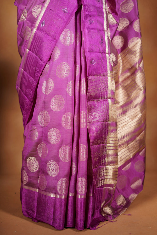Magenta  Fancy semi jute saree - It features an elegant gold zari border with fine woven detailing and a matching zari pallu. The body has small round gold butta motifs, evenly spread for a subtle  traditional look with a matching blouse.