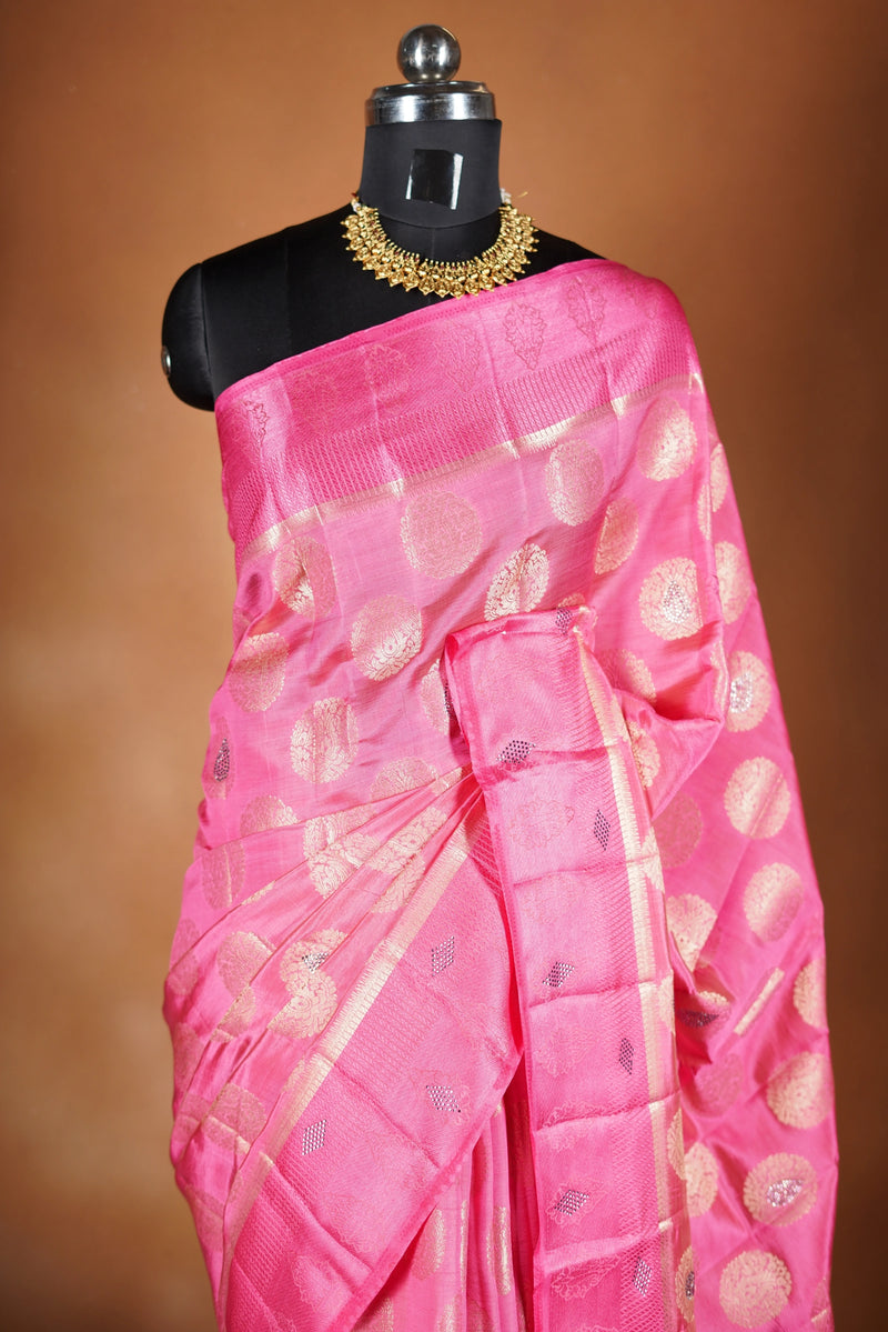 Blush Pink  Fancy semi jute saree - It features an elegant gold zari border with fine woven detailing and a matching zari pallu. The body has small round gold butta motifs, evenly spread for a subtle, graceful traditional look with a matching blouse.
