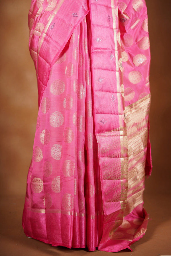 Blush Pink  Fancy semi jute saree - It features an elegant gold zari border with fine woven detailing and a matching zari pallu. The body has small round gold butta motifs, evenly spread for a subtle, graceful traditional look with a matching blouse.