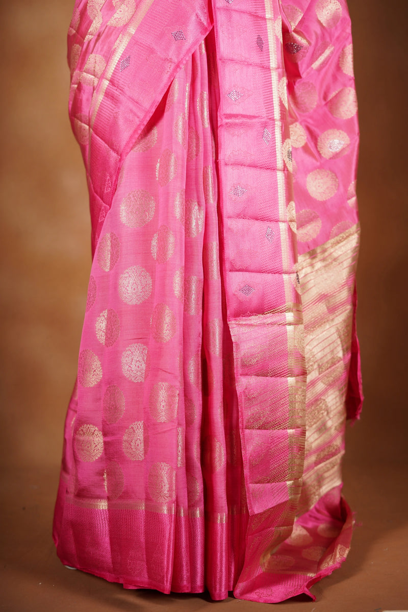 Blush Pink  Fancy semi jute saree - It features an elegant gold zari border with fine woven detailing and a matching zari pallu. The body has small round gold butta motifs, evenly spread for a subtle, graceful traditional look with a matching blouse.