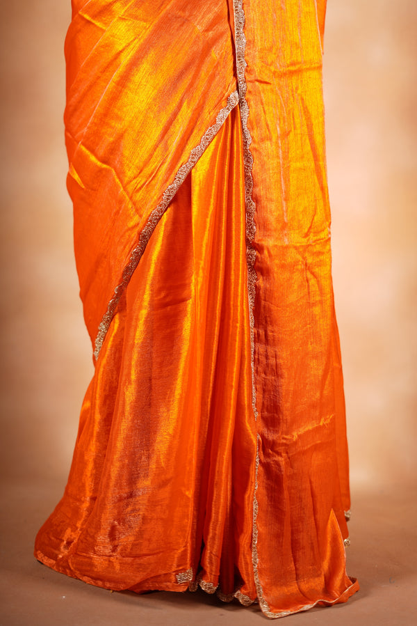 Pop Orange Space Silk Saree – Make a bold statement with this vibrant saree, featuring a smooth glossy finish. Enhanced with a delicate zari border and solid blouse, its lightweight feel blends modern style with traditional elegance for festive occasions.