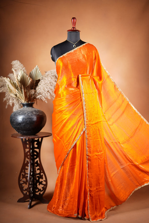 Pop Orange Space Silk Saree – Make a bold statement with this vibrant saree, featuring a smooth glossy finish. Enhanced with a delicate zari border and solid blouse, its lightweight feel blends modern style with traditional elegance for festive occasions.