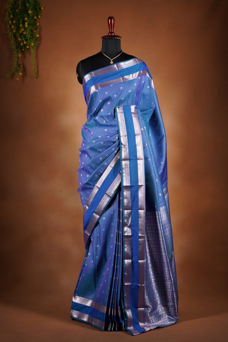 Royal blue soft silk saree featuring a modern checkered body design with elegant silver zari border and striped pallu. Lightweight and graceful, it blends contemporary geometric style with traditional elegance.