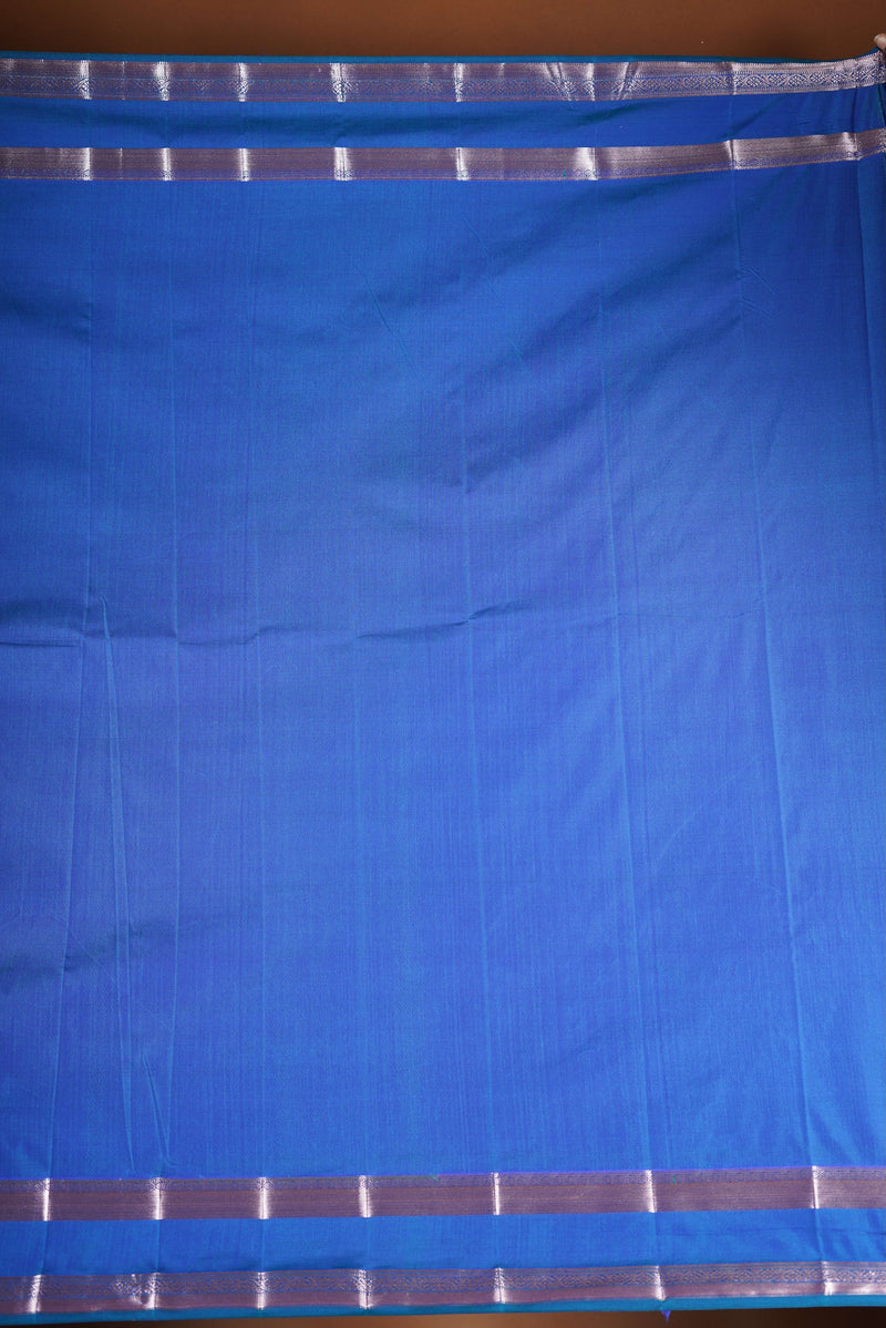 Royal blue soft silk saree featuring a modern checkered body design with elegant silver zari border and striped pallu. Lightweight and graceful, it blends contemporary geometric style with traditional elegance.