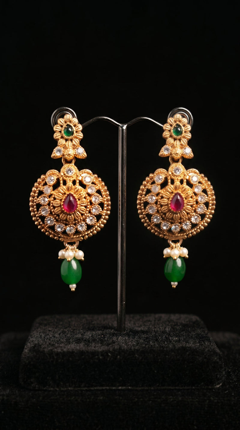 Ornate gold earrings with gemstones on a black background