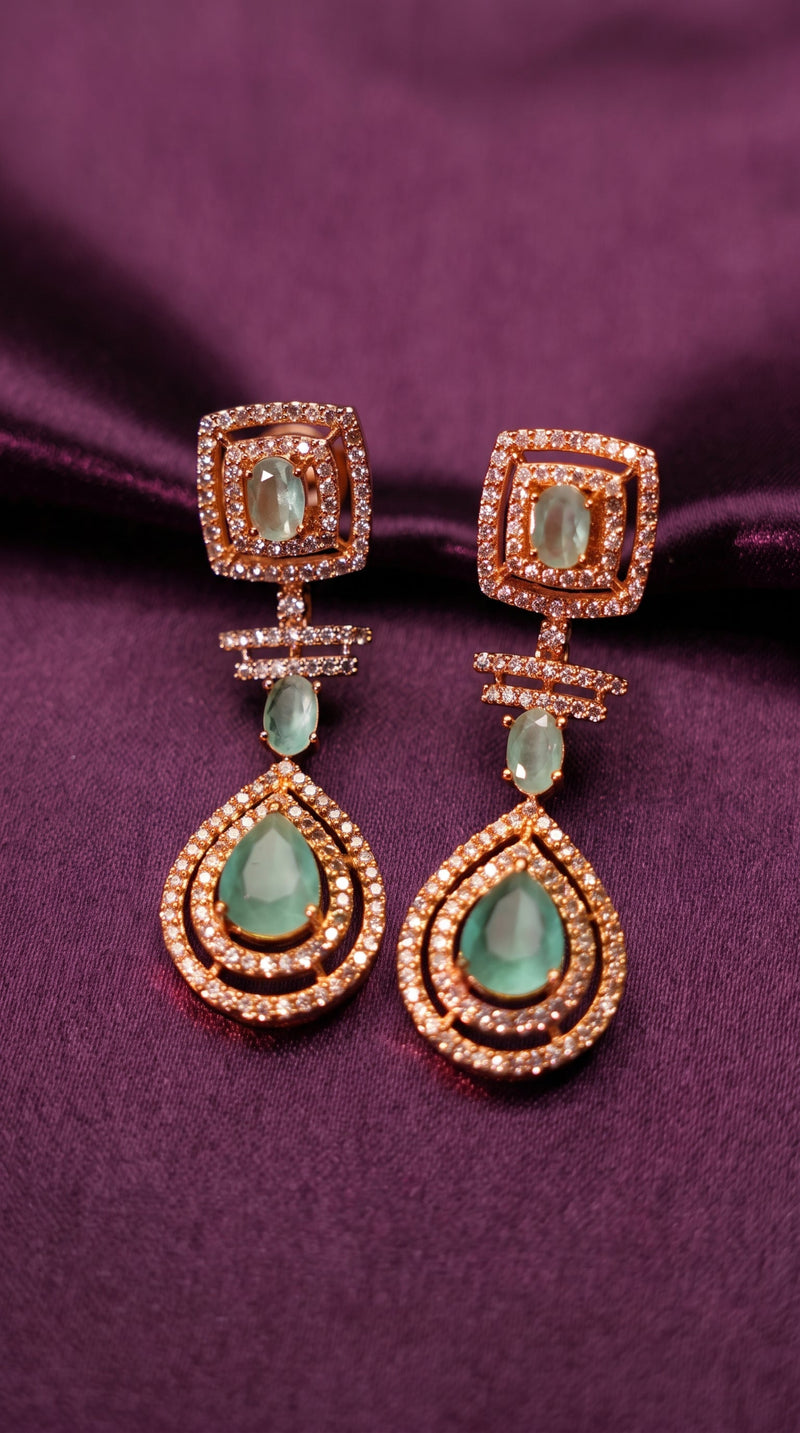Pair of earrings with green gemstones on a purple fabric background