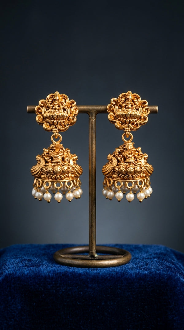 Gold earrings with pearl drops on a dark background