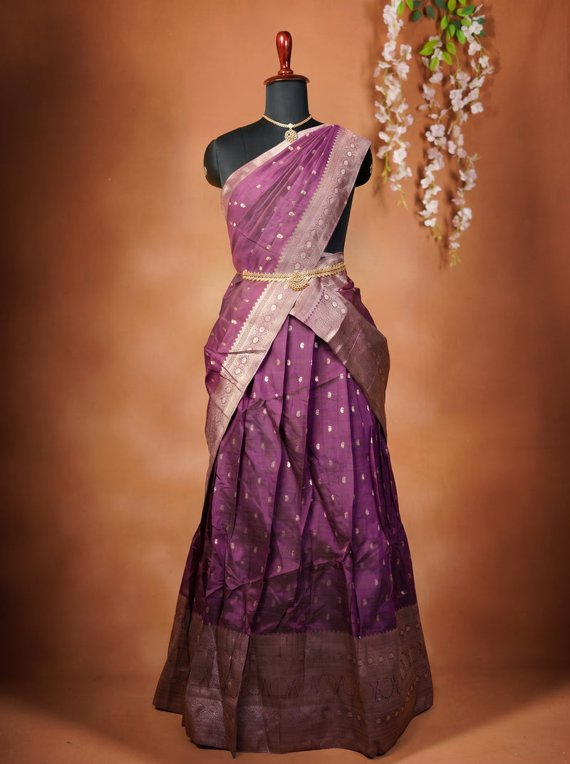 A purple and lavender silk saree with gold zari embroidery and a metallic gold waist belt, displayed on a black mannequin torso against a warm brown studio backdrop.